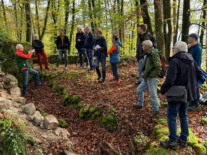 Menschengruppe im Wald vor Mauerresten